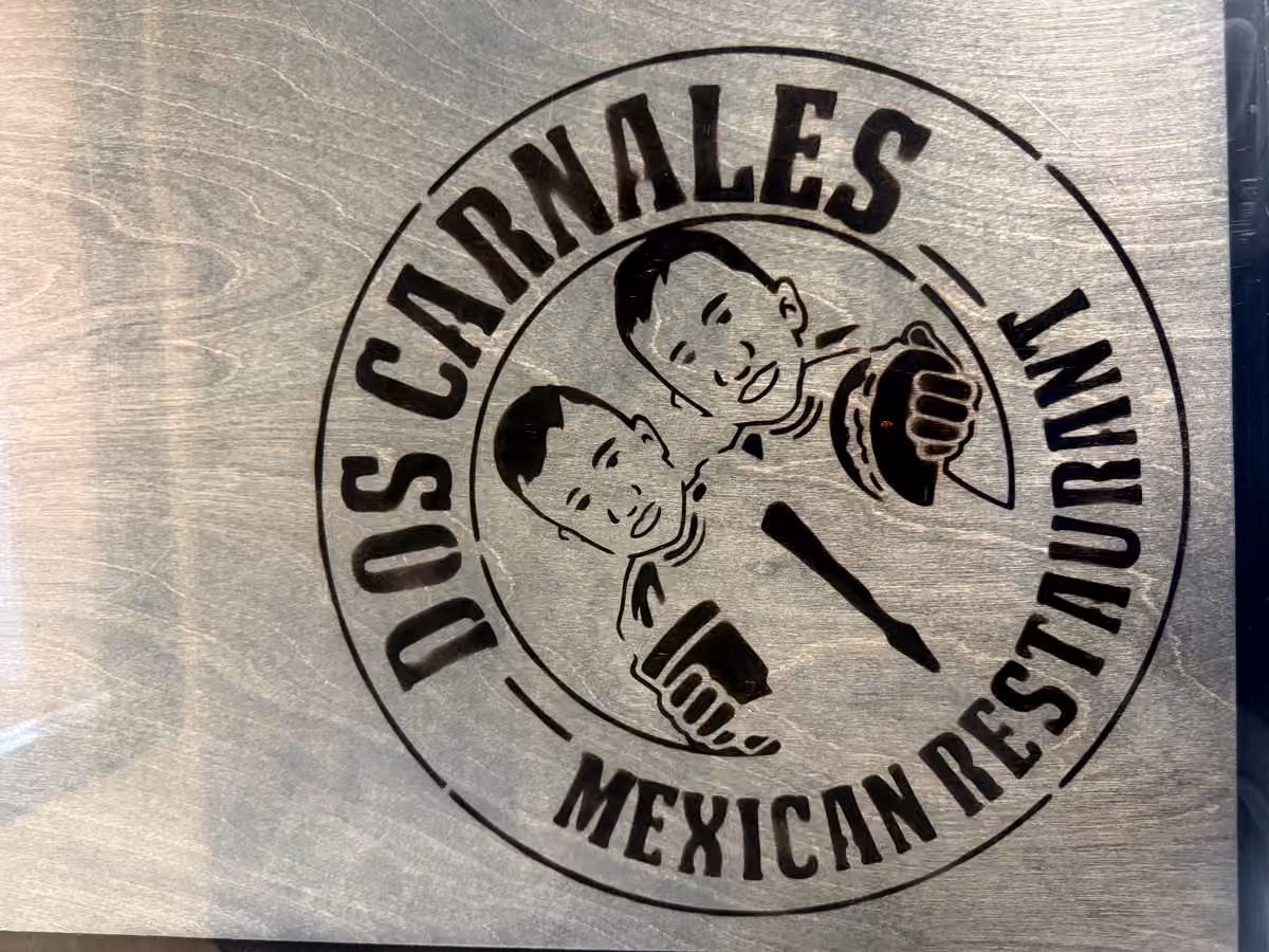 Engraved wooden plaque of the Dos Carnales mark in the dining room