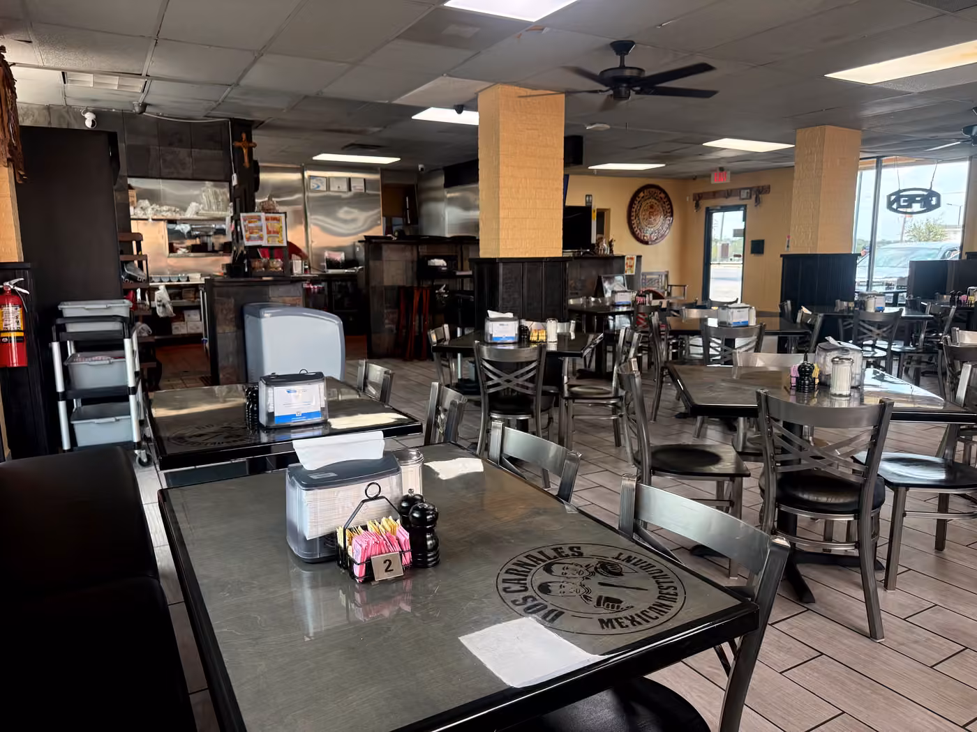 Tacos Dos Carnales dining room with tables and the engraved mark